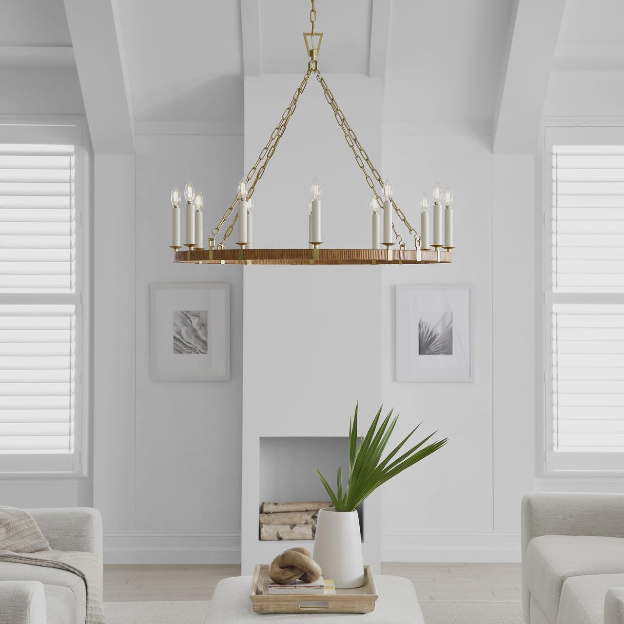 Modern candelabra chandelier in brass finish hanging in the center of a living room with white walls and decor.