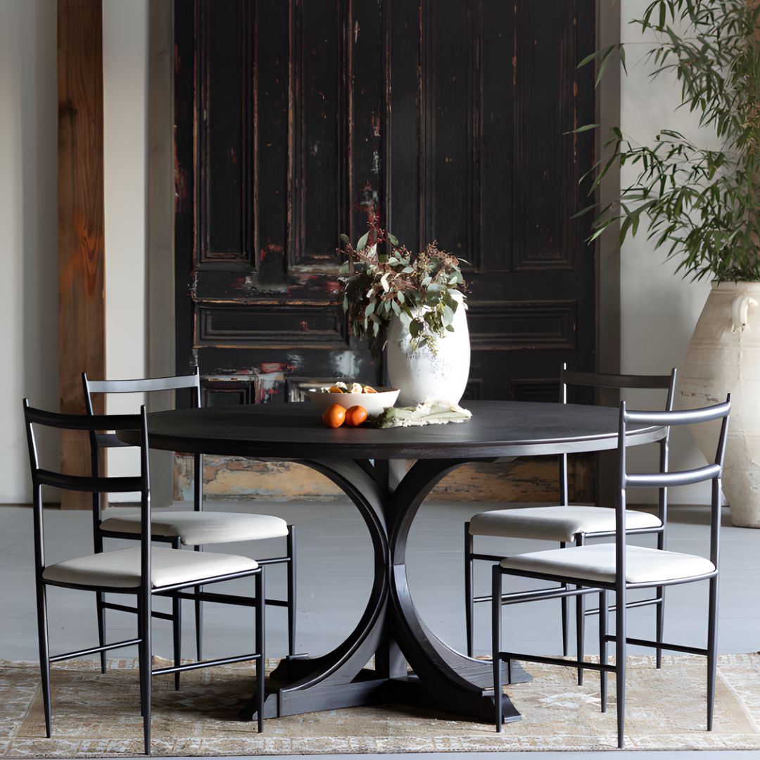 Adams Round Dining Table styled with four Ward dining chairs, accented by a decorative plant and bowls filled with nectarines.