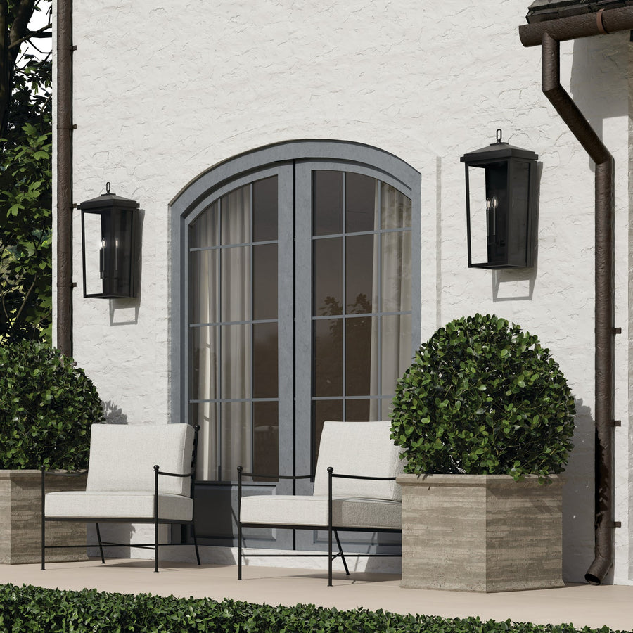 An outdoor patio with seating, featuring two Donnelly Outdoor Wall Lanterns flanking the patio door.