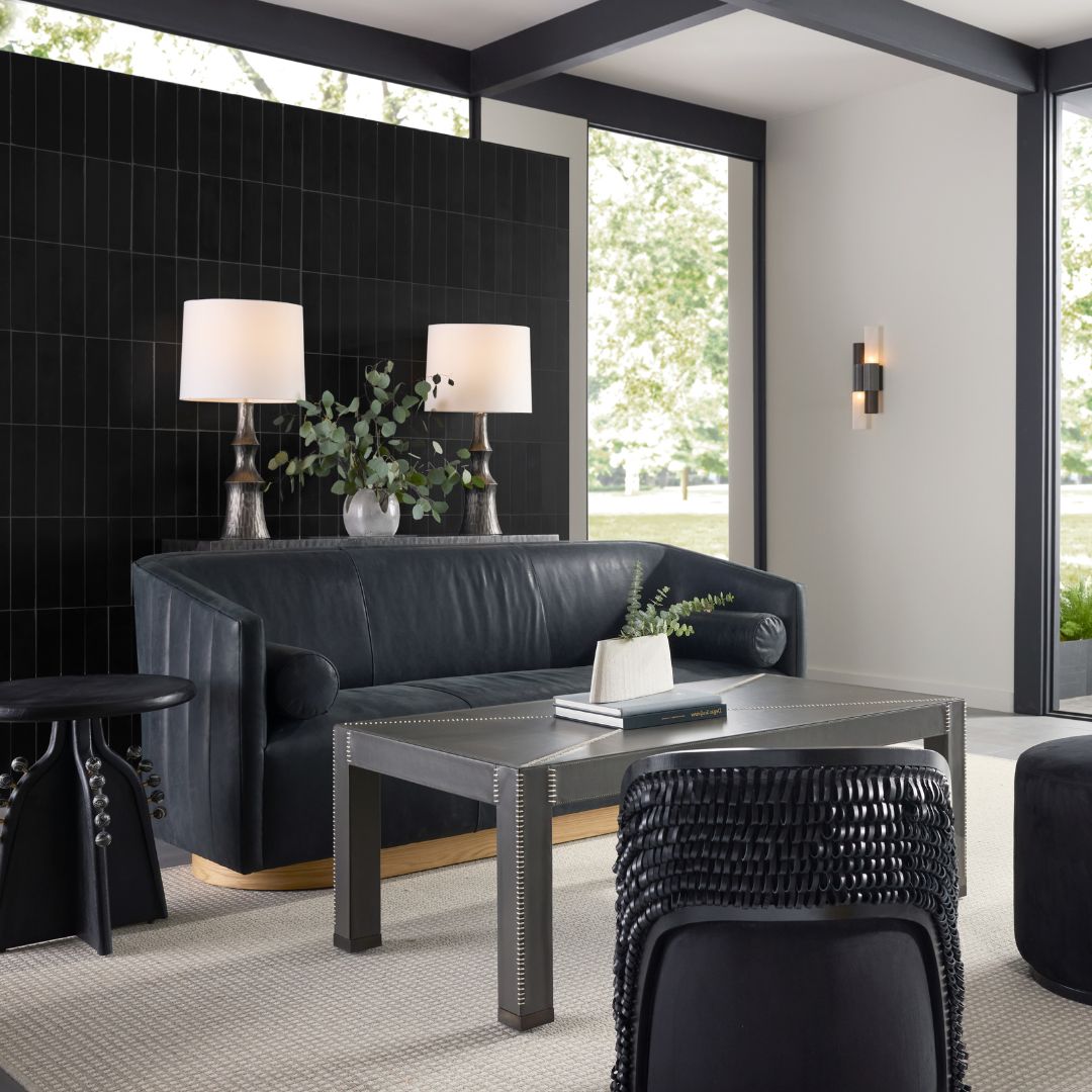 Huxley Sofa in Noir Leather White Oyster styled within a contemporary sitting room, accompanied by a coffee table and side table, with a console table behind featuring matching lamps and a touch of greenery.