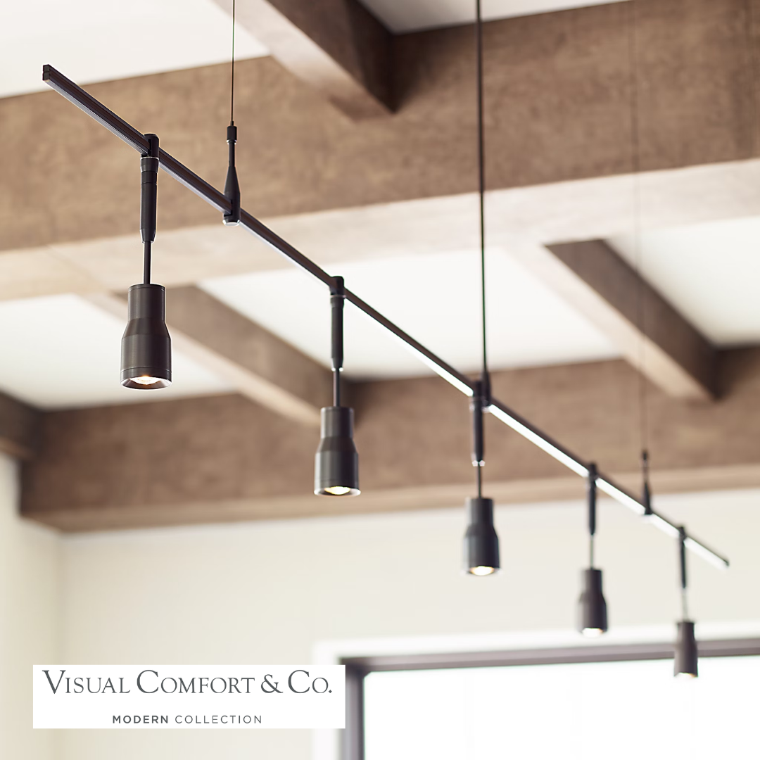 Ace Head MonoRail system with multiple heads in an antique bronze finish by Visual Comfort, set against a wooden beam ceiling backdrop.