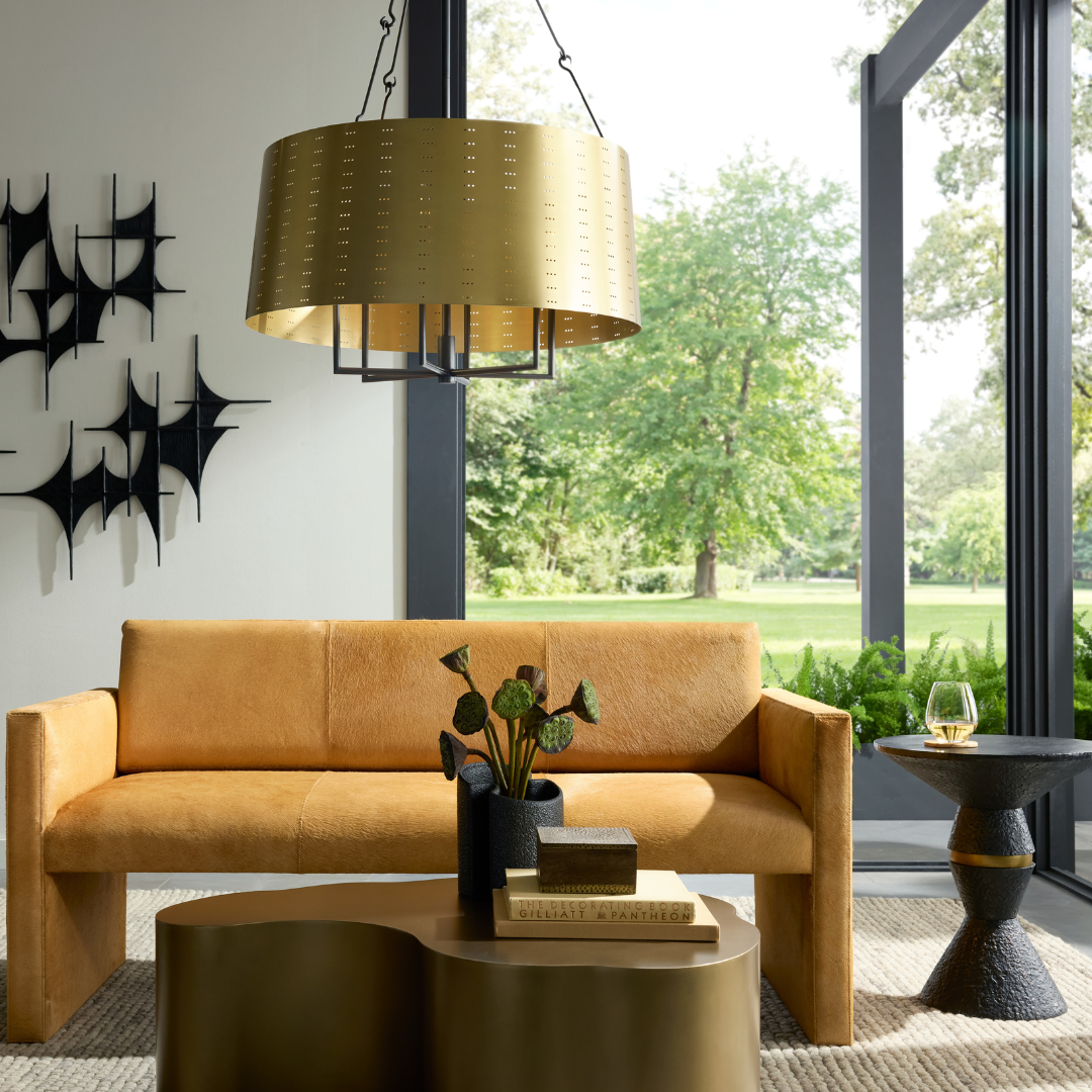 Halock Settee styled in a contemporary sitting room, paired with a coffee table and side table, centered beneath a round chandelier and framed by large open windows.