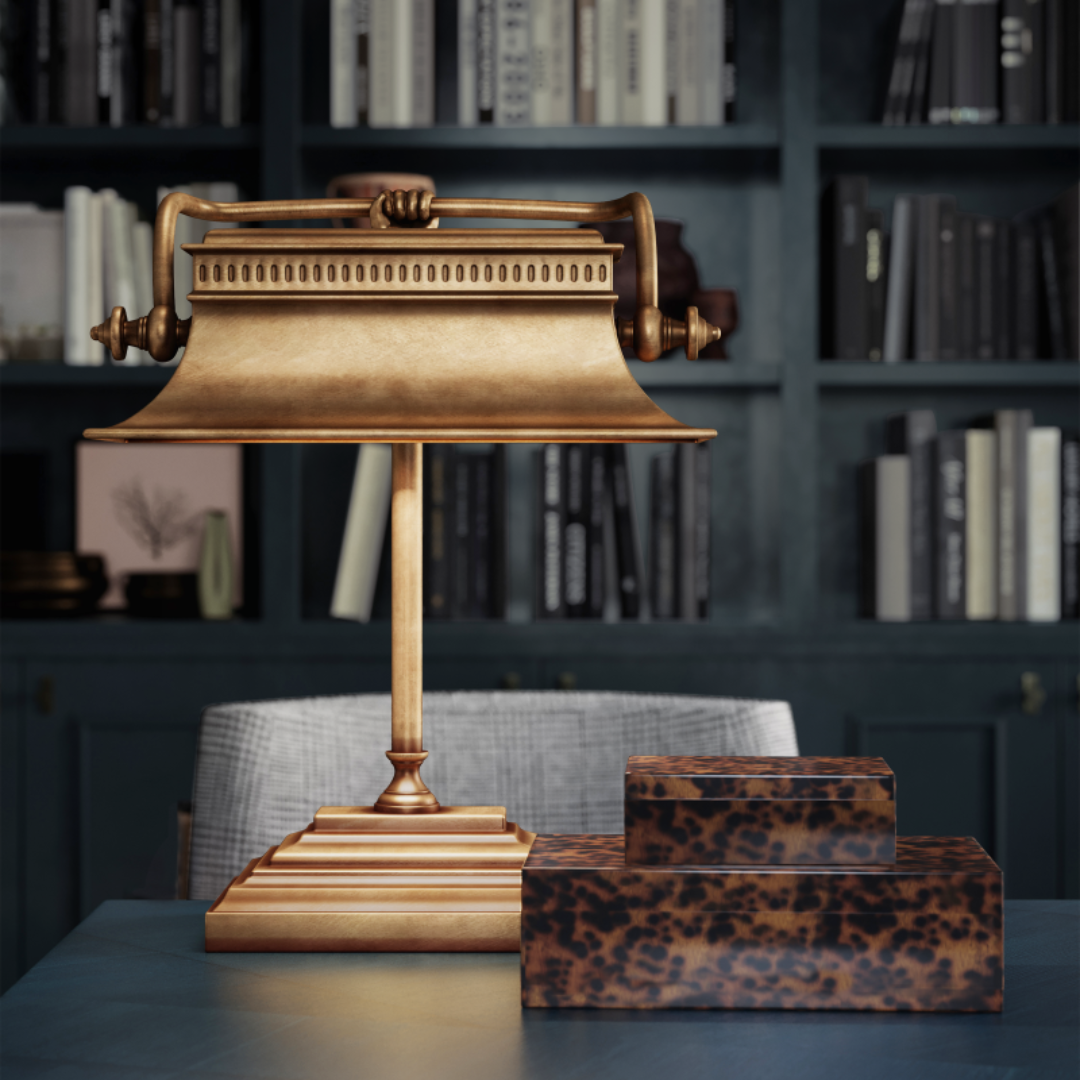 Malvasia Brass Desk Lamp styled in a contemporary office, set against fully stocked blue bookshelves and paired with a decorative box.