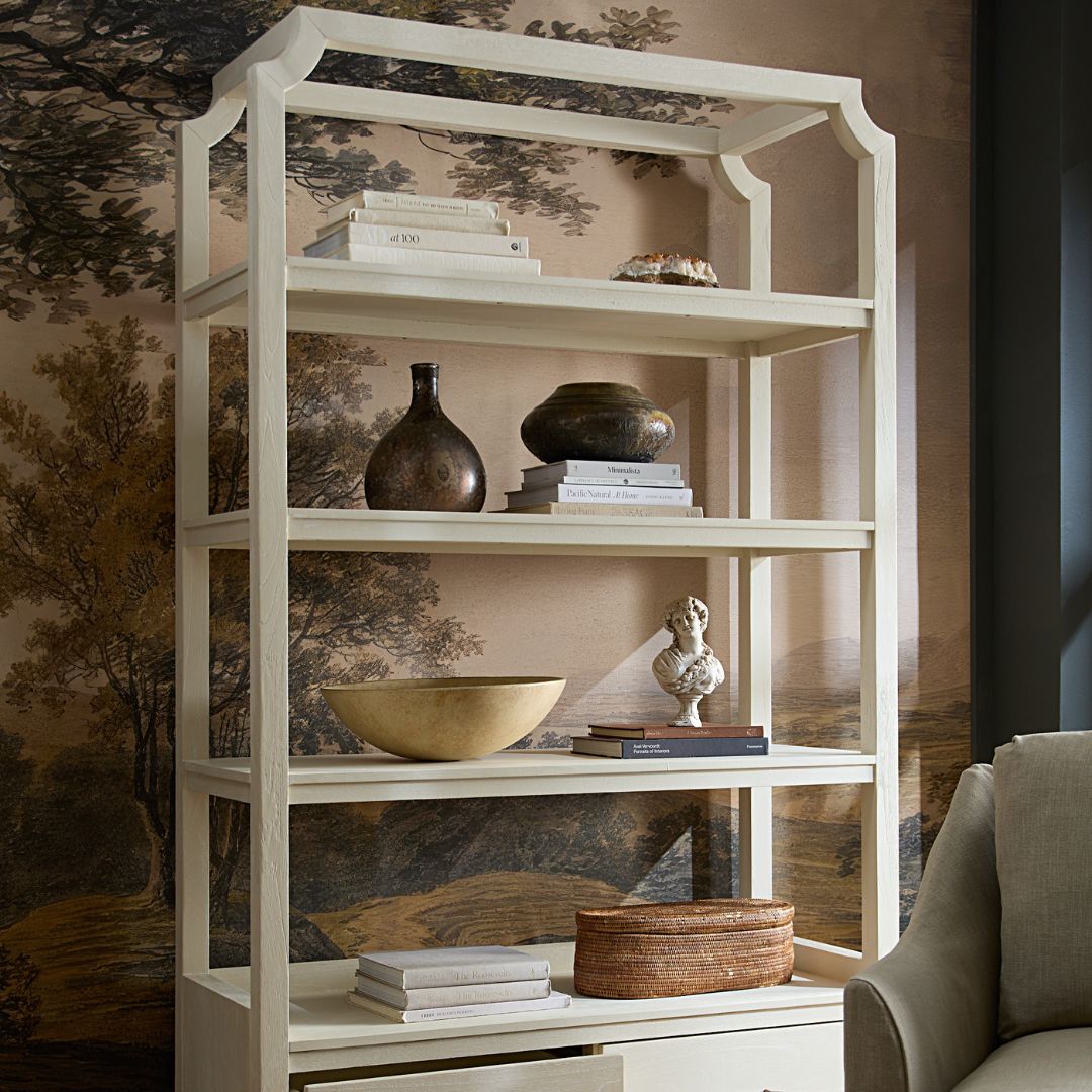 Crest Bookcase styled with books and decorative accents on each shelf, set against contemporary pink-toned wallpaper featuring a tree motif.