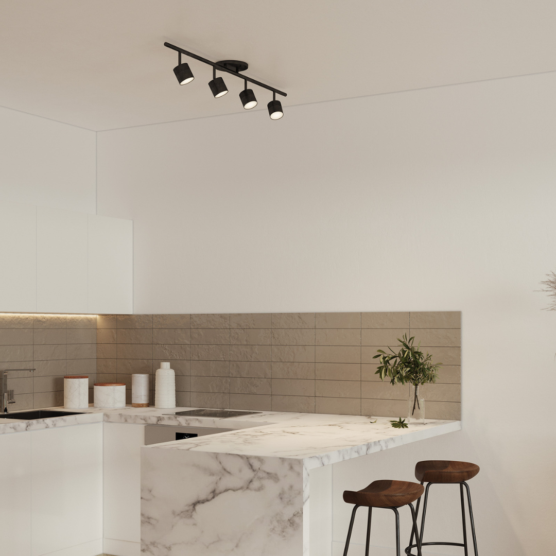 Lyra LED Track Light in a black finish styled above a marble kitchen island, paired with two wooden counter stools in a modern setting.