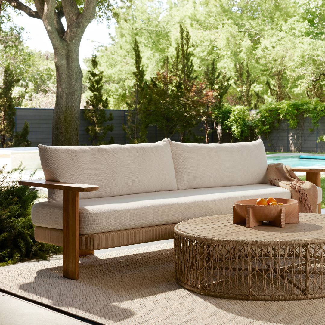 Halston Outdoor Sofa styled with the Hugo Outdoor Coffee Table on a sunlit patio during summer.