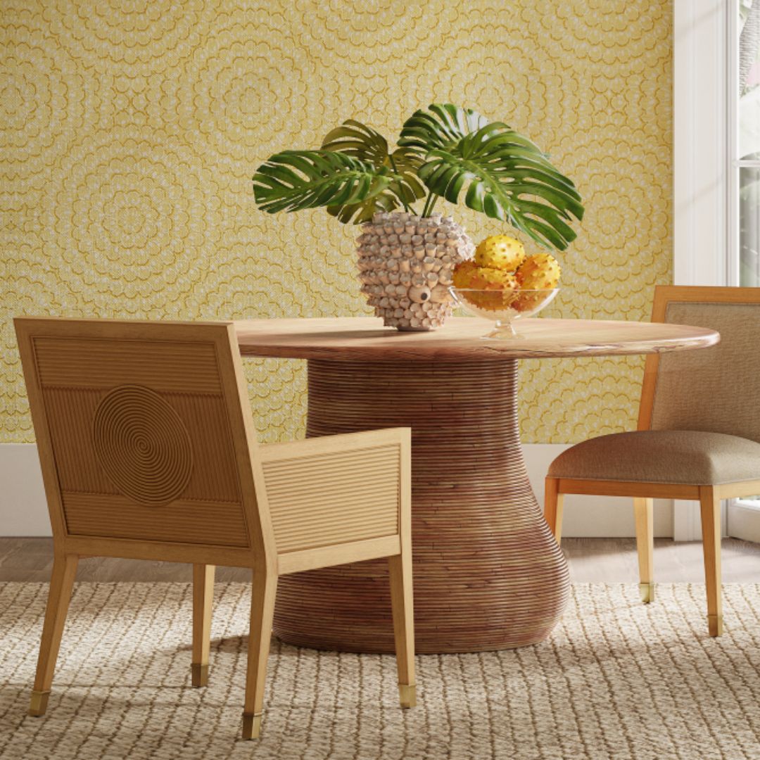 Two Santos Sea Sand Dining Chairs styled in a coastal-inspired dining room, set against a yellow accent wall and complemented by decorative plants on top.