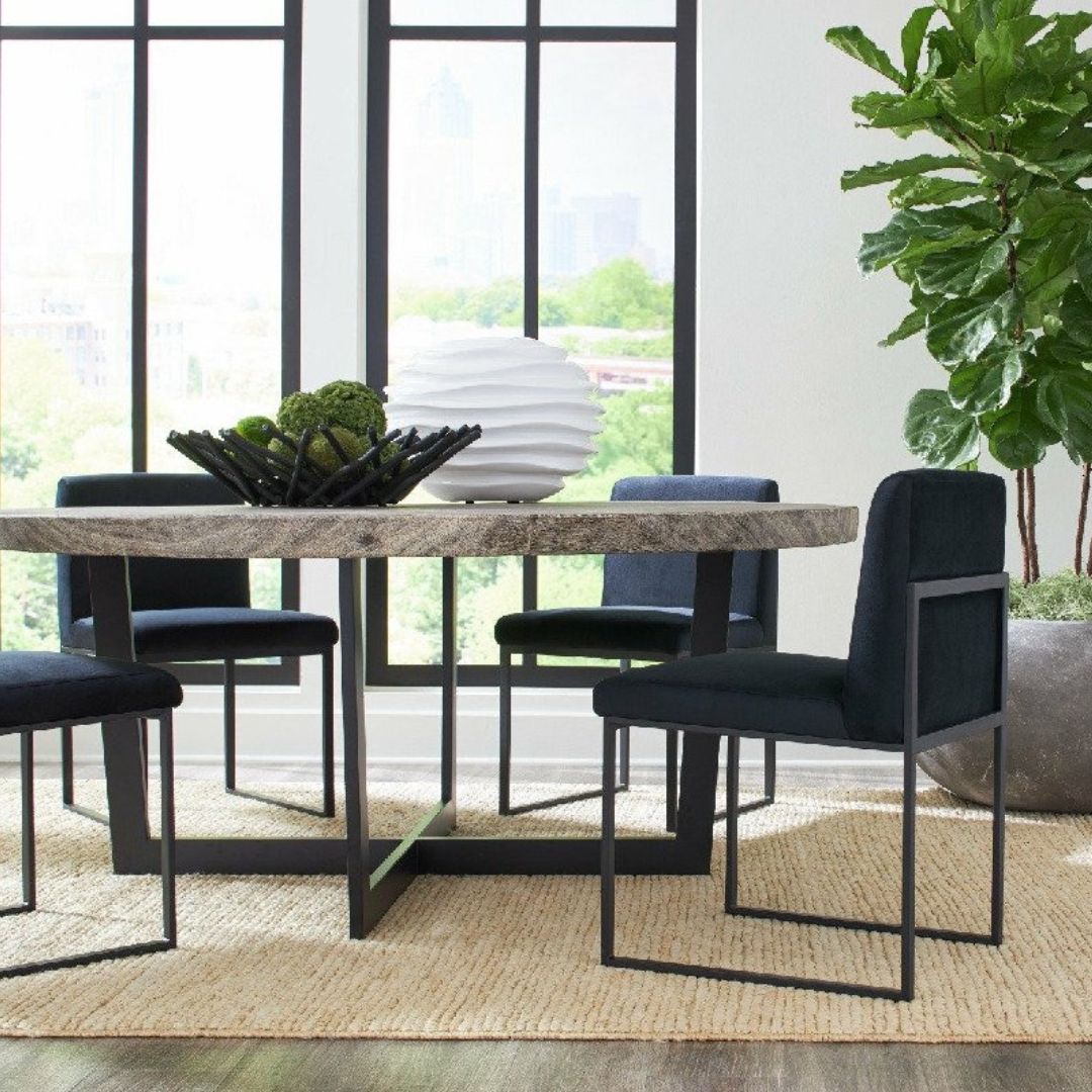 Chuleta Dining Room Table styled with a vase and decorative bowl on top, surrounded by four dining chairs and accented by a large fiddle leaf fig tree in the corner.
