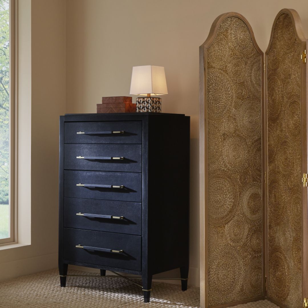 Verona Black Five-Drawer Chest styled with a table lamp and decorative boxes on top, set beside a room divider to the right.