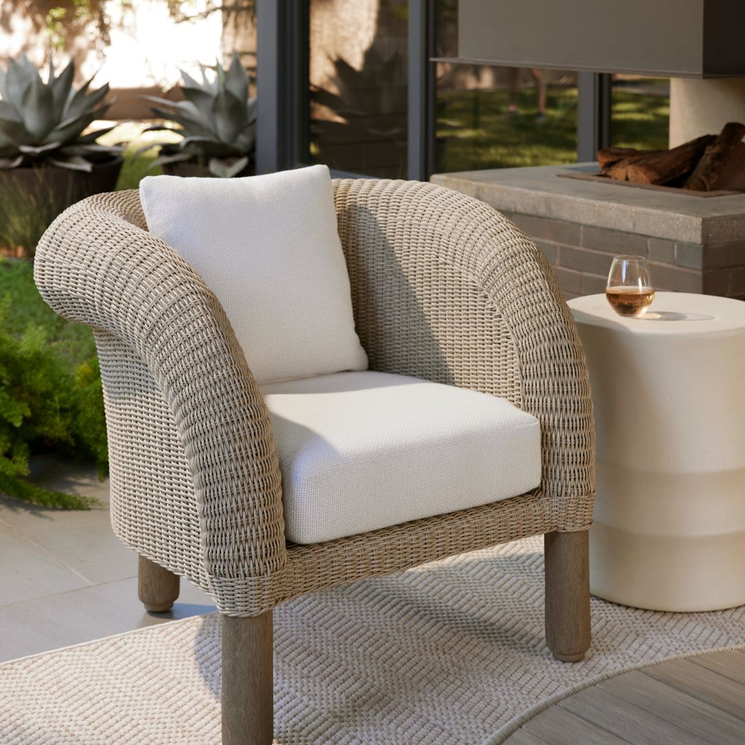 Fielder Outdoor Lounge Chair styled beside an outdoor side table topped with a stemless wine glass, set within a patio space.