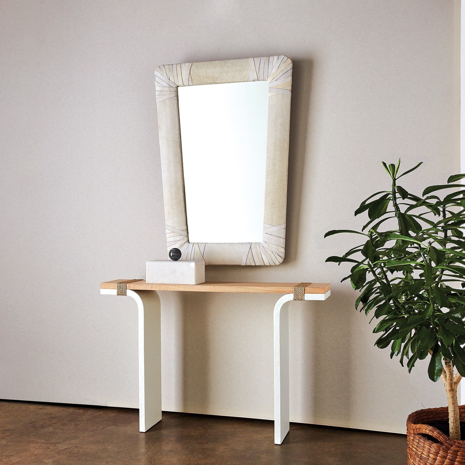 Gabriel Mirror in a white leather finish styled above a modern console table accented with a decorative box.
