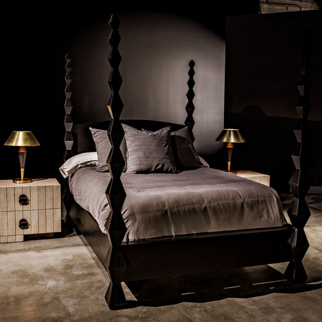 Brancusi Bed styled with gray bedding and layered pillows, paired with an ivory nightstand topped with brass table lamps.