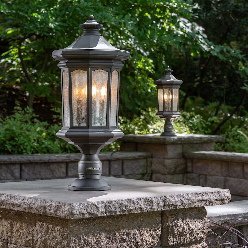 Decorative outdoor lanterns on a stone ledge with greenery in the background