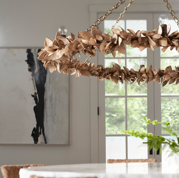 Decorative chandelier hanging above a table in a room with plants and large windows.