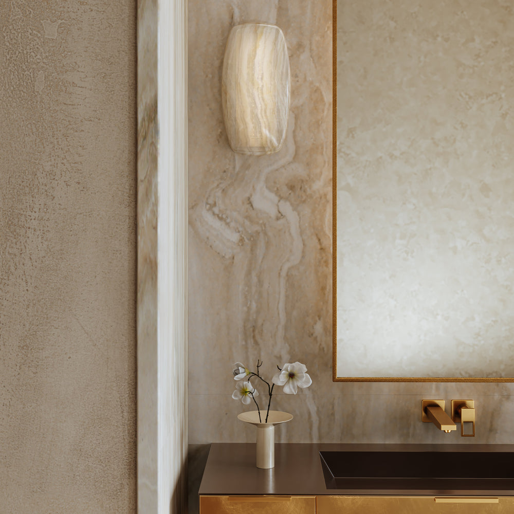 Luxurious bathroom interior with marble walls, a mirror, alabaster sconce, and decorative elements.