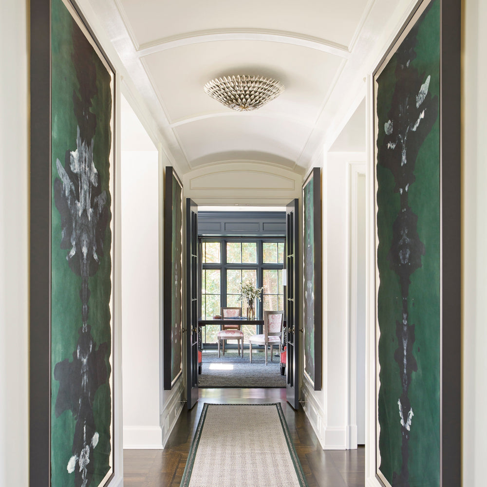Long hallway with large framed artworks on either side, a semi flush mount in the middle, leading to a room with a table and chairs.