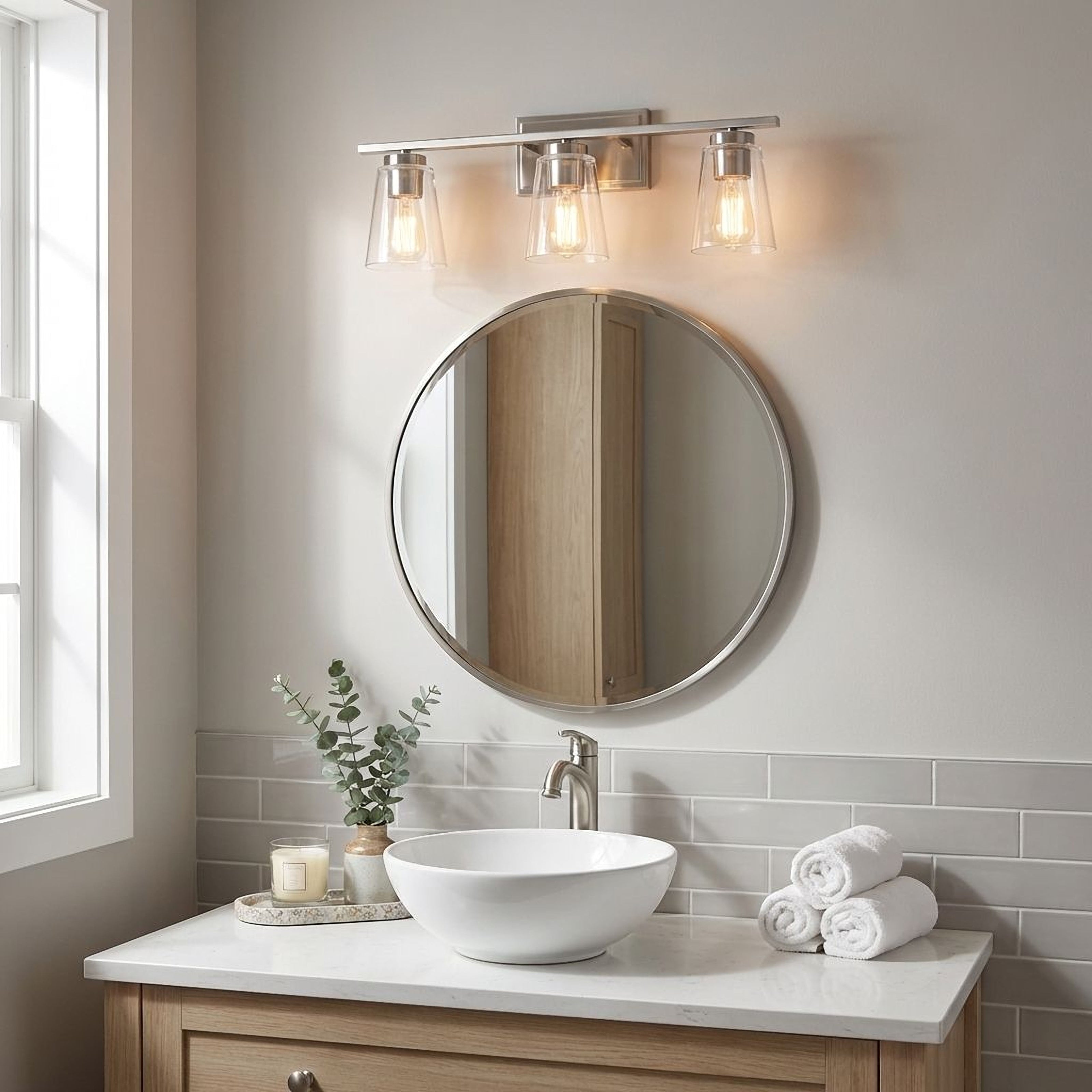 Farmhouse bathroom vanity with round mirror, silver nickel light fixture, and towels.