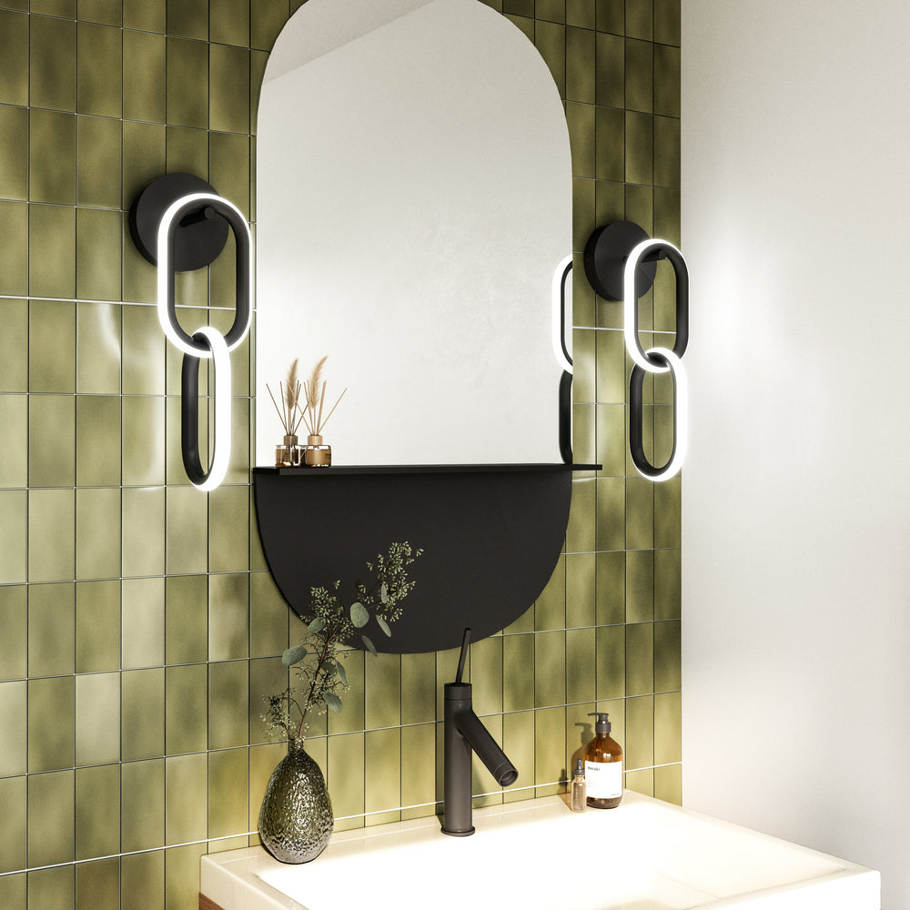 Bathroom vanity with mirror modern lights on each side, and decorative elements against a green tiled wall.