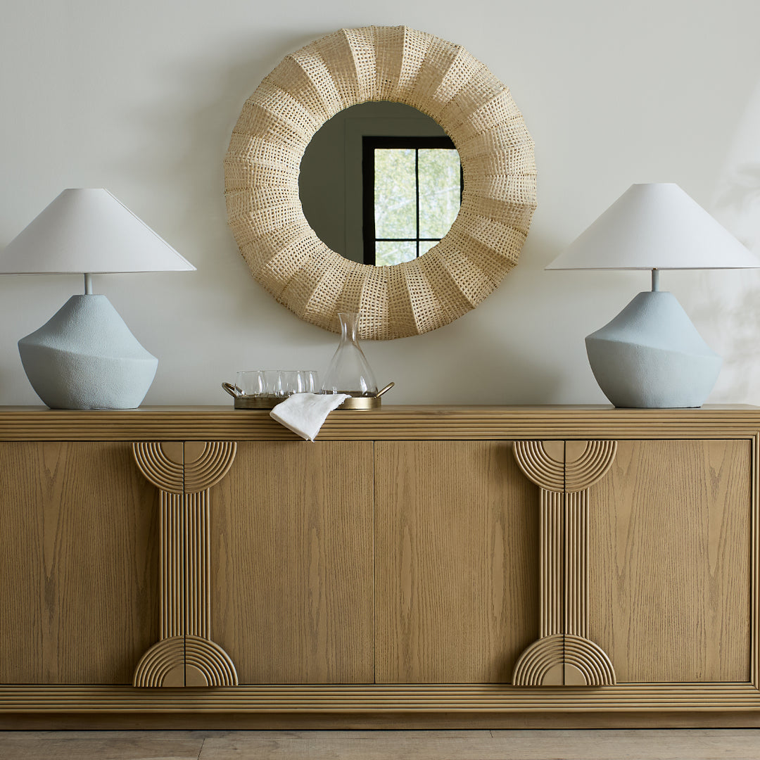 The Areo Sideboard in a natural oak veneer finish, styled with a lamp on each end and a textured decorative mirror mounted on the wall above.