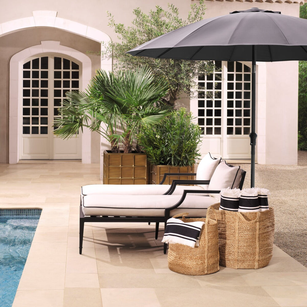 Outdoor patio setup with lounge chairs, umbrella, and decorative items by a pool.