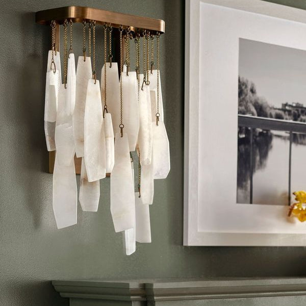 Wall-mounted  sconce with white glass shades on a green wall with a framed picture over a fireplace mantel.