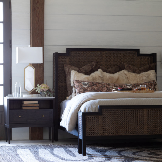 Bedroom with wooden bed, nightstand, and decorative pillows.