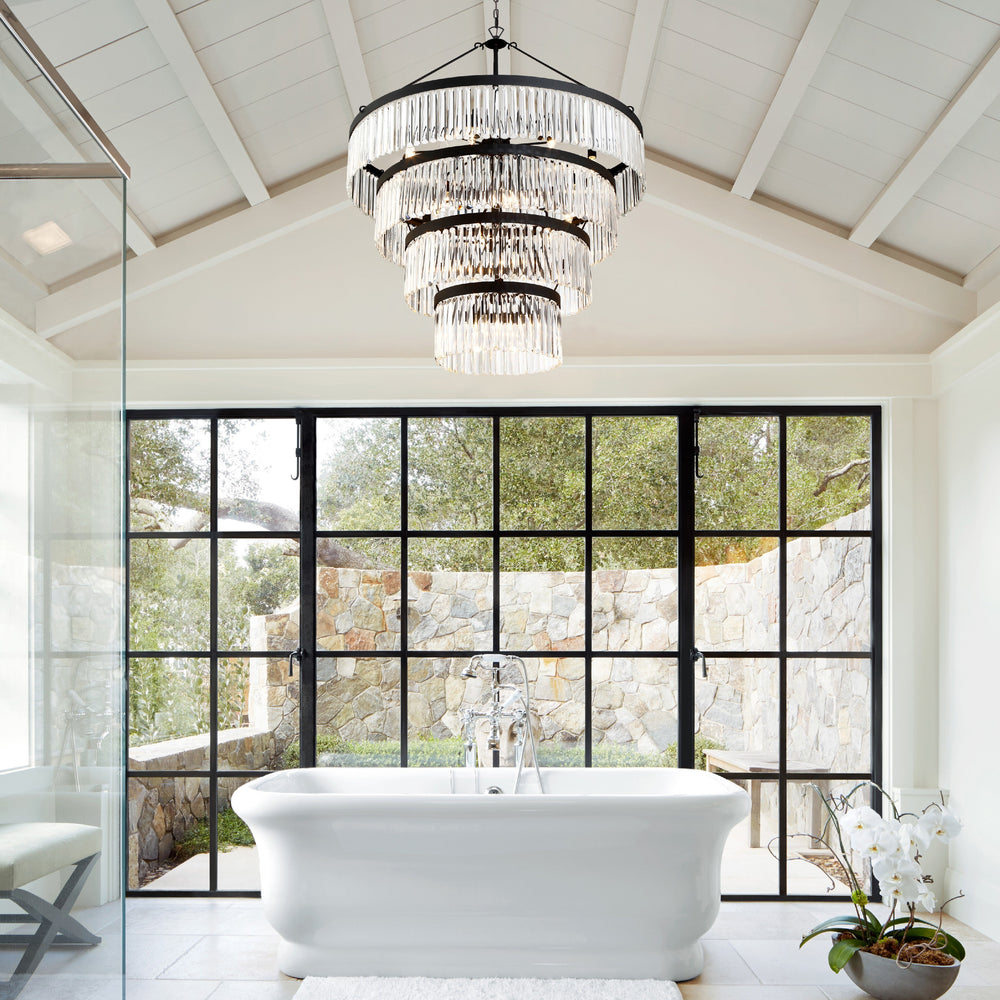 Modern bathroom with freestanding bathtub, large window, and grand chandelier.