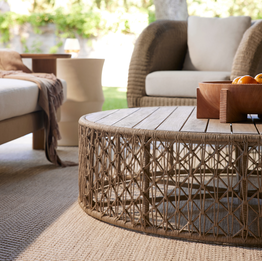 Wicker coffee table with a bowl of oranges in an outdoor setting