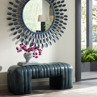 Decorative mirror with floral arrangement on a entryway bench.