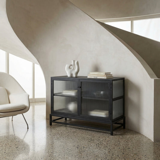 Noir Chandler 2 Door Sideboard Matte Black with fluted glass doors beneath a curved plaster staircase