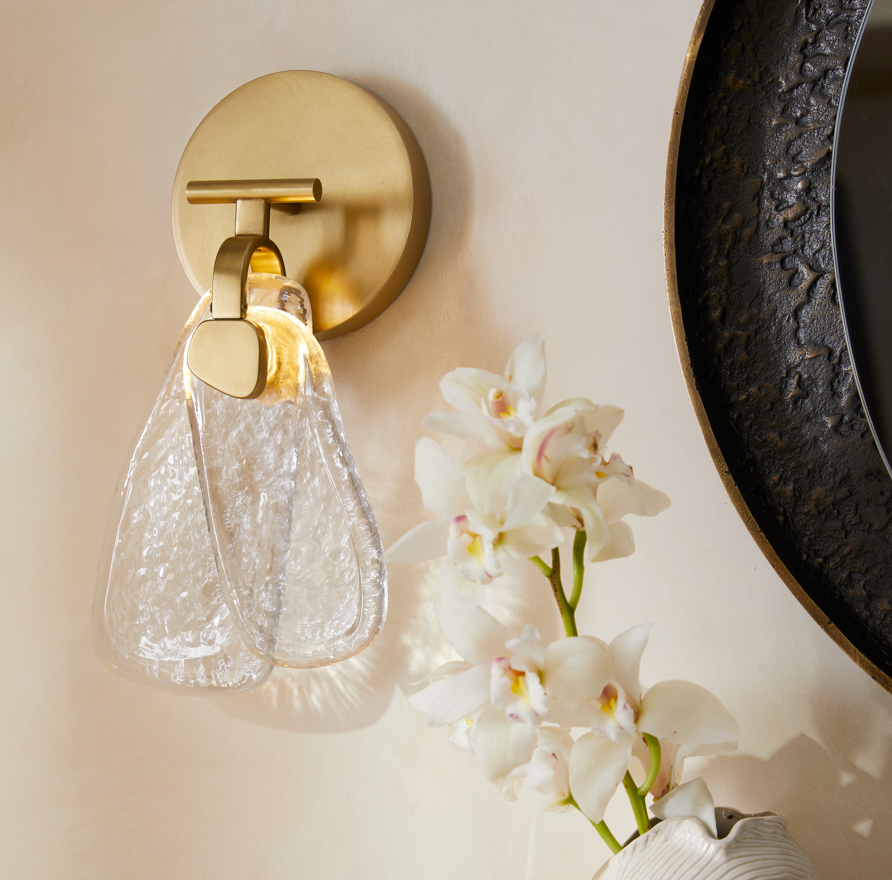 Decorative wall sconce with a vase of white flowers on a neutral colored wall.
