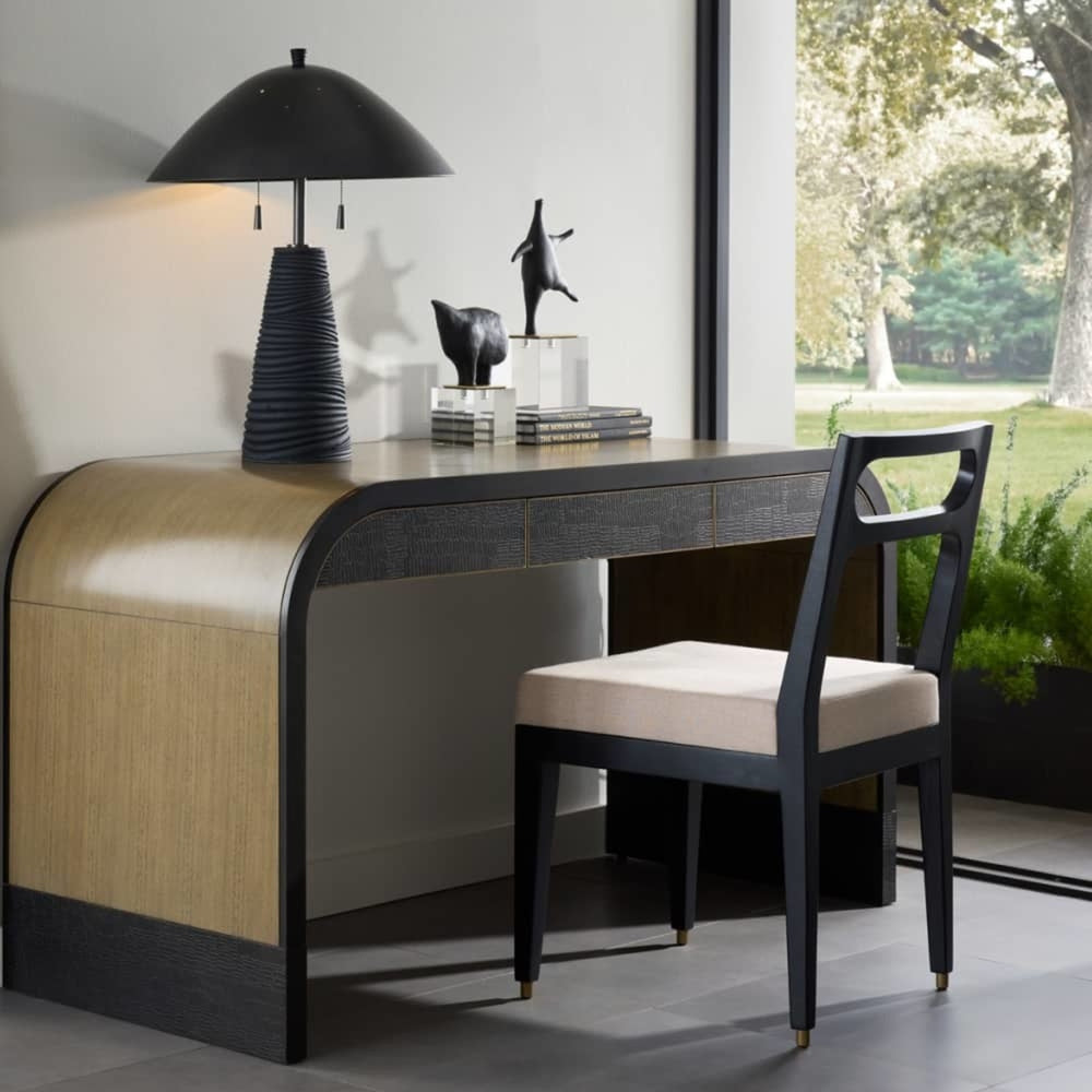 Midcentury styled desk with a chair and a table lamp in a office space with a window view.