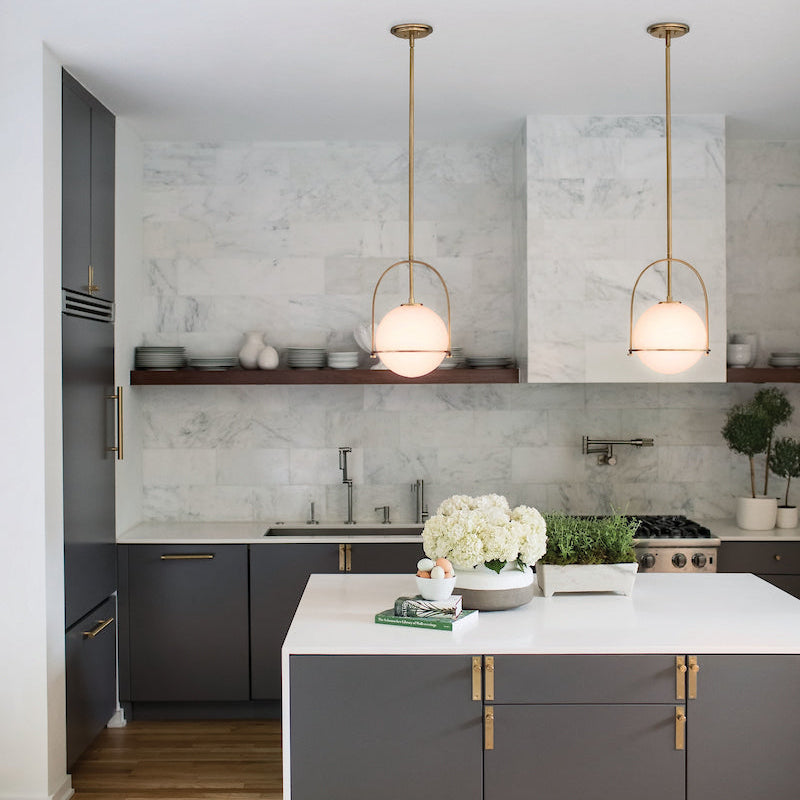 Modern kitchen with gray island, white countertops, gold accents and two Somerset Pendants over the island.