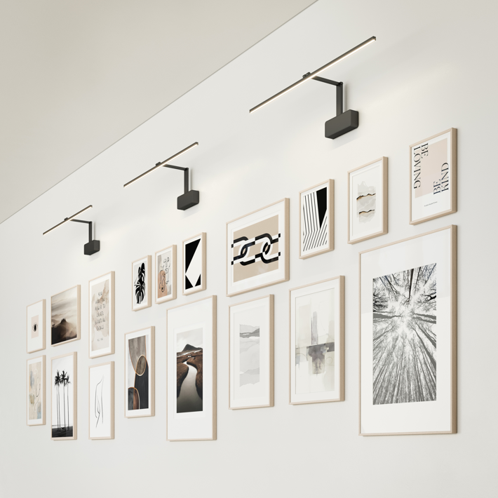 Hallway featuring a wall with wooden framed pictures and modern picture lights.