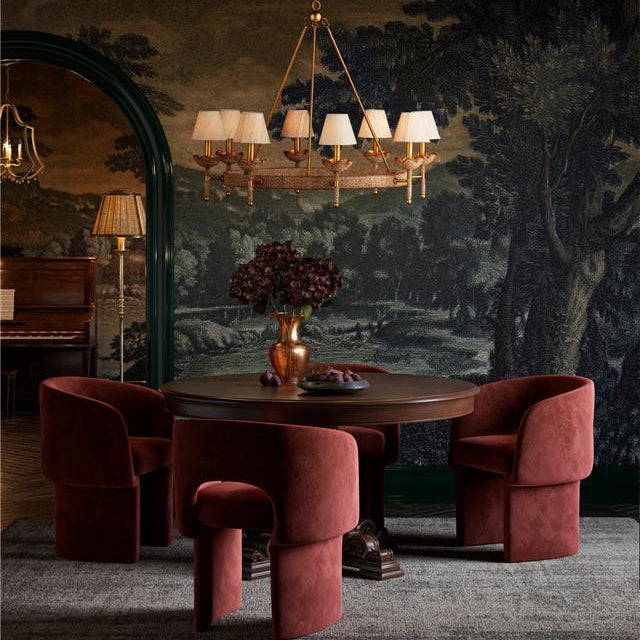 Dining room with round table and red chairs against a decorative wall.